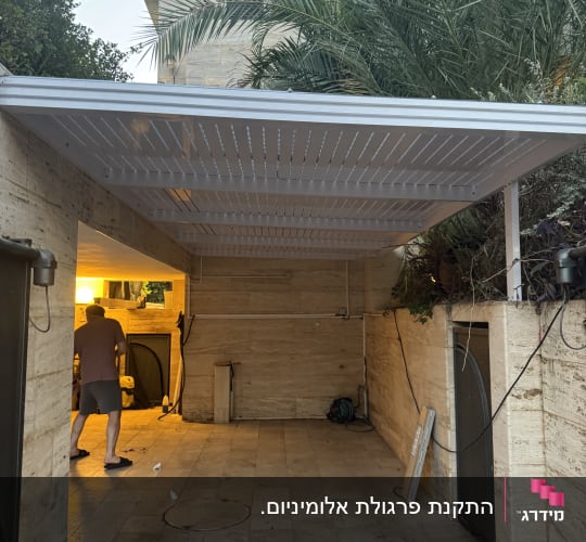חניה מקורה מאלומיניום לבן המותקנת מעל אזור חניה בבית פרטי